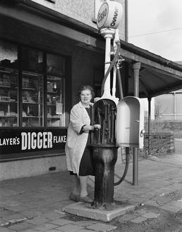 Mrs Clague at petrol pumps, Andreas stores