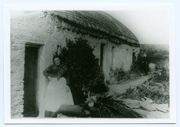 Woman outside a thatched cottage