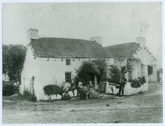 Family group outside a thatched cottage