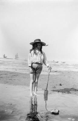 Girl paddling on Douglas shore, holding a spade