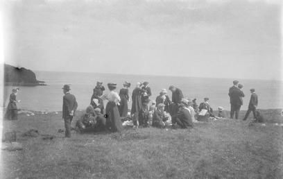 Picnic party gathered on cliff-top overlooking the sea…