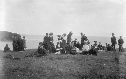 Picnic party gathered on cliff-top overlooking the sea…