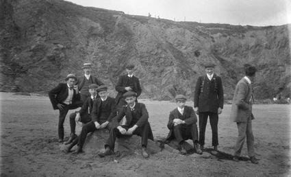 Group of clothed men sitting on rocks near…