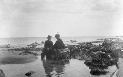 Two women sitting on rocks at water's edge