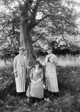 Three women in formal pose in front of…