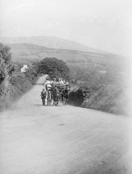 Carriage with two horses and passengers descending hill…
