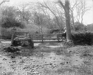 Fairy bridge over stream with person seated right