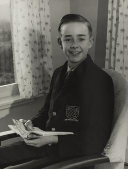 Paul Cain, in school uniform, seated indoors