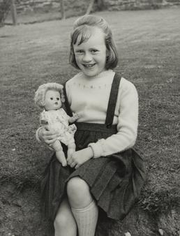 Susan Gelling, seated with doll outdoors