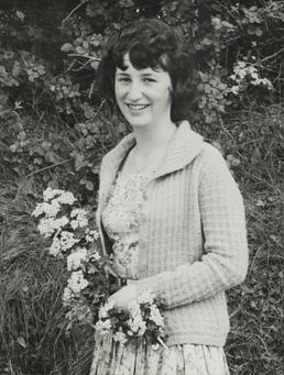 Lynne Kneale, standing outdoors holding flowers