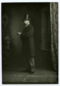 Mr Archibold Knox, standing in top hat and…