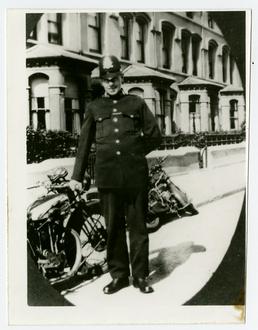 Tom Lowey - standing outside in police uniform
